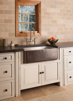 a kitchen sink sitting under a window next to a counter top with drawers underneath it