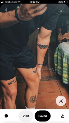 two people standing next to each other with tattoos on their legs and one holding a cell phone