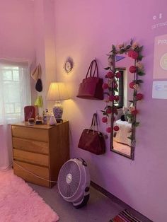 a room with pink walls and purple rugs on the floor next to a dresser