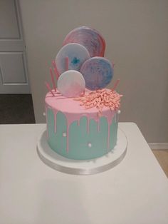 a pink and blue cake sitting on top of a white table