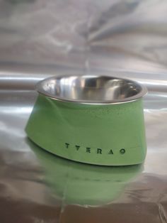 a green bowl sitting on top of a shiny surface with the word terra written in it