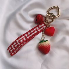 a strawberry keychain with a red and white ribbon attached to it's side