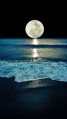 the moon is shining over the ocean with waves coming in to shore and dark blue water