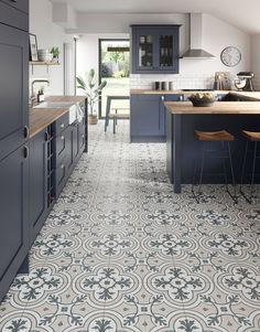 a kitchen with blue cabinets and an ornate tile flooring pattern on the wall, along with bar stools