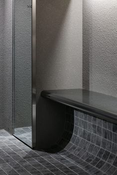 a bathroom with a glass shower stall and tiled flooring, along with a black bench