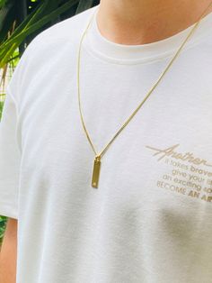 a man wearing a white t - shirt and a gold necklace with a rectangle pendant