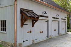 an old white barn with three doors and a brown awning on the side of it