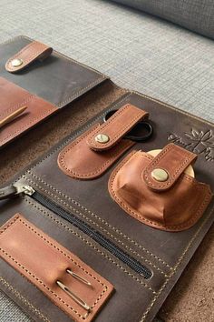 two brown leather wallets sitting on top of a couch next to a pair of scissors