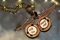 two gold lockes with words on them and an angel's wing hanging from the chain