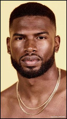 a close up of a man with a beard and no shirt on wearing a necklace