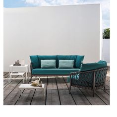 a blue couch sitting on top of a wooden floor next to a white table and chair