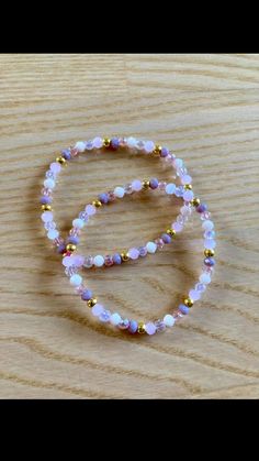 a beaded bracelet with pink and gold beads on a wooden surface, resting on a table