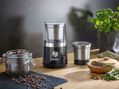 a coffee maker sitting on top of a wooden table next to a potted plant