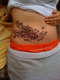 a woman's stomach with a flower tattoo on the side and an orange belt around her waist