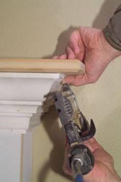 a man is working on the base of a wall with a drill and screwdriver