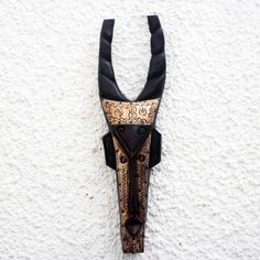 a black and gold mask hanging on the wall next to a white stucco wall,