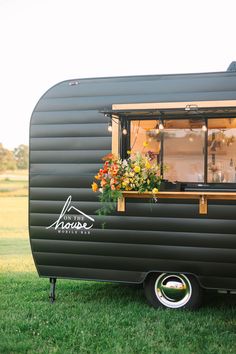 an old camper converted into a mobile home with flowers in the window and potted plants outside