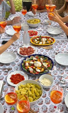 a group of people sitting around a table with food and wine glasses in front of them