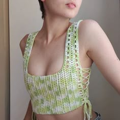 a woman with short hair wearing a crochet top and denim shorts is posing for the camera