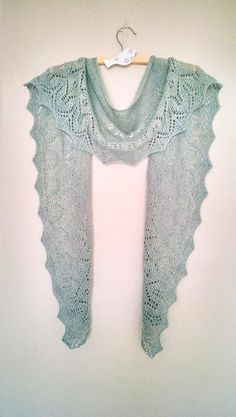 a light blue shawl hanging up on a white wall next to a hanger