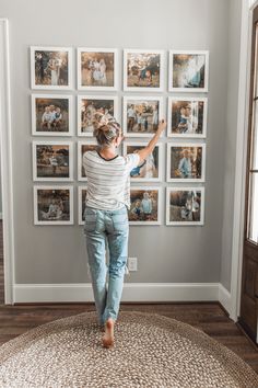 a woman standing in front of a wall with pictures on it