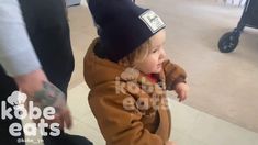 a small child in a brown jacket and hat