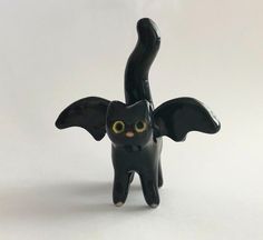 a black cat figurine with yellow eyes and wings