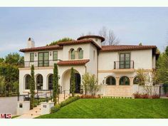 a large white house sitting on top of a lush green field