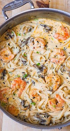 pasta with shrimp and mushrooms in a skillet on a wooden counter top, ready to be eaten