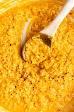 a wooden spoon in a bowl filled with yellow food