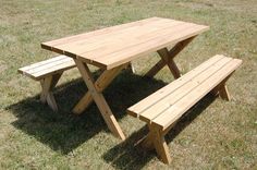 a wooden picnic table and bench in the grass