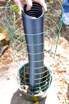 a person is holding a large pipe in a wire mesh basket on top of a rock