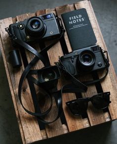 an old camera and some other items sitting on a wooden pallet next to each other