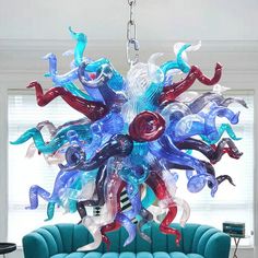 a chandelier hanging from the ceiling over a blue couch in a living room