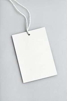 a white tag hanging from a string on top of a gray surface with an empty piece of paper attached to it