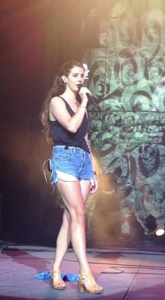 a woman in high heels on stage singing into a microphone