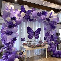 a purple and white balloon arch decorated with butterflies