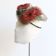 This sumptuous 1940's percher hat, adorned with three central millinery red velvet roses, green millinery leaves decorated with forest green tulle and tulle ribbon accents, on a woven straw base, is the perfect piece to complete your outfit.  Her textured shape is constructed on a rounded woven straw and wire base. The circular wire base along the back of the percher allows for the hat to be placed securely upon any do. Every last detail of this hat showcases the incredible millinery work of the Vintage Spring Headband, Vintage Headband For Kentucky Derby, Vintage Handmade Flowers Fascinator For Party, Vintage Summer Headband, Vintage Spring Headpieces For Races, Vintage Headpieces For Spring Races, Spring Vintage Headpieces For Races, Vintage Headpieces For Royal Ascot Races, Tulle Ribbon