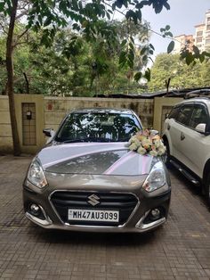 a silver car parked next to a white car with flowers on it's hood