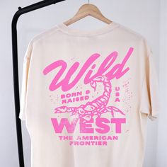 🤠Embrace the spirit of the Wild West with our "Wild West Born & Raised" graphic tee! This vintage-inspired shirt features a bold pink design that pays homage to the rugged American frontier. Perfect for your country concert or your night out in Nashville! 🔥 Stand Out in Style: Whether you're hitting the rodeo or just hanging out with friends, this graphic tee is sure to turn heads and start conversations. Pair it with your favorite jeans or shorts for a casual yet cool look that's perfect for any occasion.  🖤SHIRT MATERIAL Comfort Colors Unisex Shirt 100% Ring-Spun Cotton Printed using Direct To Garment style- Inks are printed directly into the fabric. Different sizing may effect placement of final design. Colors may differ slightly due to different user monitor and screen settings.  🏁 Country Concert Tshirts, Retro Graphic Shirt, Female Graphic Tees, One Color T Shirt Designs, Conference Shirt Design, Concert T Shirt Design, Concert Tee Design, Trendy Oversized T Shirts, Fun Shirt Designs