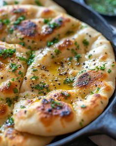 a close up of a pizza in a pan with cheese and herbs on the top