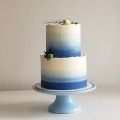 a three tiered cake with blue and white frosting