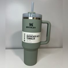 a green travel mug with a straw sticking out of it