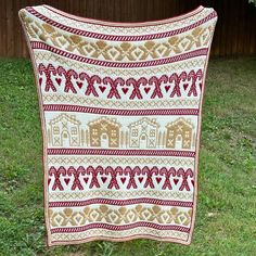 a blanket that is on the grass in front of a wooden fence with an elephant and heart motif