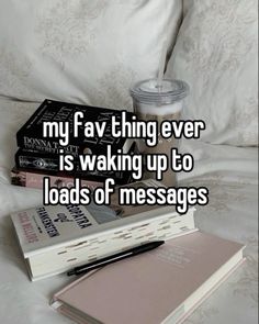 a stack of books sitting on top of a bed next to a cup