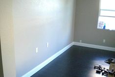 an empty room with hard wood flooring in the middle and a window on the far wall