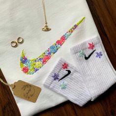 two pairs of white socks with flowers on them next to a necklace and earring