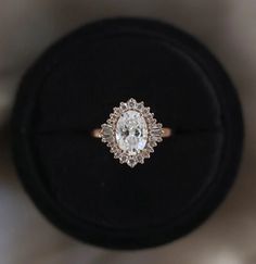 an engagement ring with a diamond center sits on a black velvet box, top view