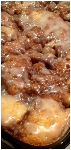 a close up of a cake in a pan with icing and cinnamon rolls on top