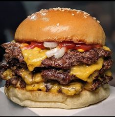 a cheeseburger with onions and ketchup sitting on top of a table